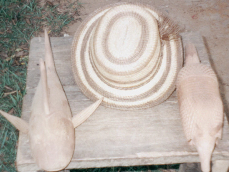 Un sombrero en fibra y figuras en madera tallada